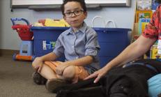 kid with autism sits beside a therapy dog